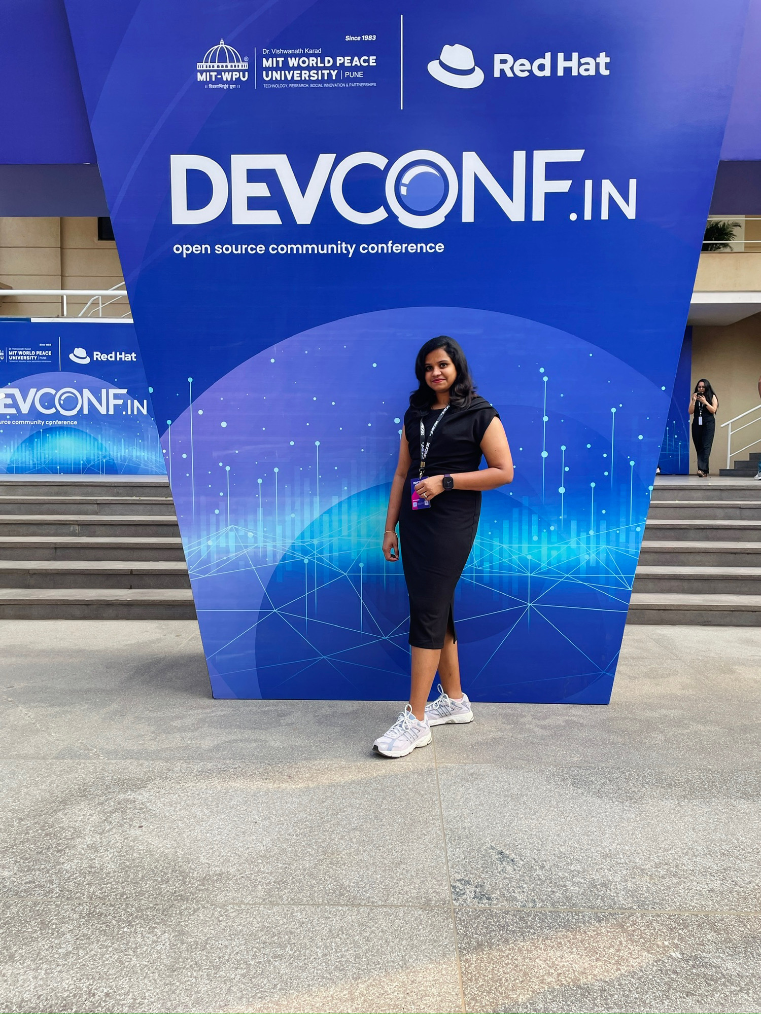 Portrait photo of Arathy Kumar smiling, framed against a clean modern slatted architectural feature background.